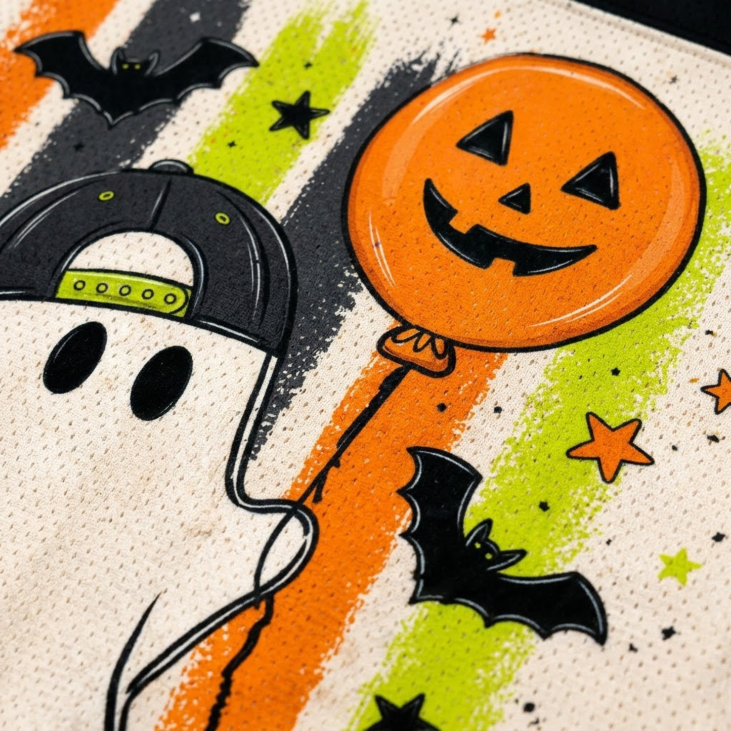 Macro close-up shot of the graphic print on mesh fabric, focusing on the high-definition details of the ghost's snapback cap, pumpkin balloon, candy corn, and brushstrokes.
