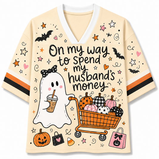 Front view of the cream varsity jersey displaying 'On my way to spend my husband's money' text with a cute ghost holding coffee and pushing a shopping cart full of pumpkins.