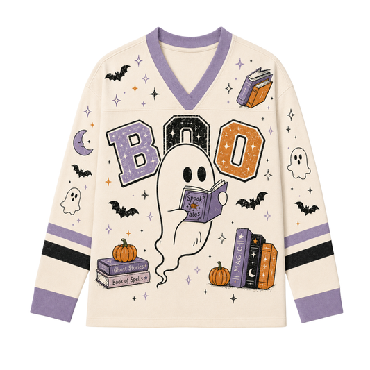 Front view of the cream long sleeve jersey displaying a cute ghost reading Spook Tales under BOO varsity letters with stacks of magic spellbooks, pumpkins, and bats.