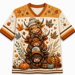 A short-sleeve V-neck graphic T-shirt with an all-over autumn-themed illustration featuring three stacked Highland cows, pumpkins, leaves, stars, and plaid accents in warm fall colors on an off-white base.