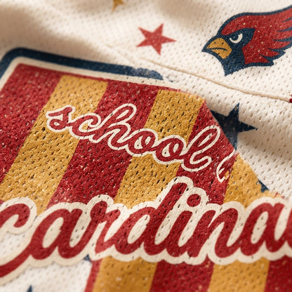 Close-up of a cream-colored athletic jersey featuring a red and gold striped patch with the words 'school cardina' in red script, plus a red cardinal head logo and navy star details.