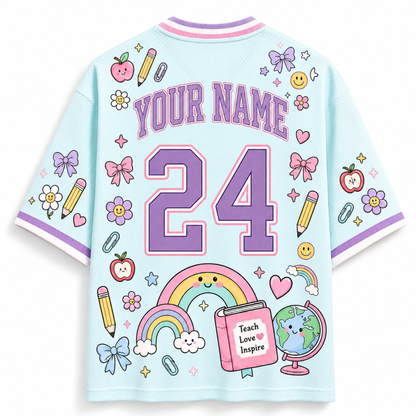 A light blue mesh short-sleeve t-shirt shown from the back, featuring a customizable design with purple text reading 'YOUR NAME', the number '24' in purple, and various colorful school-themed illustrations including rainbows, pencils, bows, flowers, and a book.