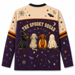A long-sleeve crewneck sweatshirt shown from the back, featuring a Halloween-themed graphic with the text 'THE SPOOKY SQUAD' above four dogs dressed as a witch, mummy, hot dog, and ghost. The top half is beige with spiderwebs and paw prints, and the bottom half is dark purple with orange and purple accents.