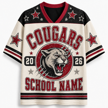 A short-sleeve V-neck athletic-style shirt with a distressed collegiate graphic. The design features a cream base, black shoulder and sleeve sections, red trim, and a large front graphic with the word 'COUGARS', a cougar head, numbers '20' and '26', stars, and the text 'SCHOOL NAME'.