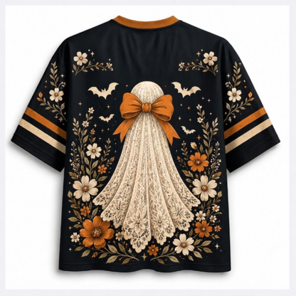 A black short-sleeve t-shirt with a graphic of a ghost in a cream lace dress and large orange bow, surrounded by orange and white flowers, bats, and leaves. The sleeves have orange and cream stripes.