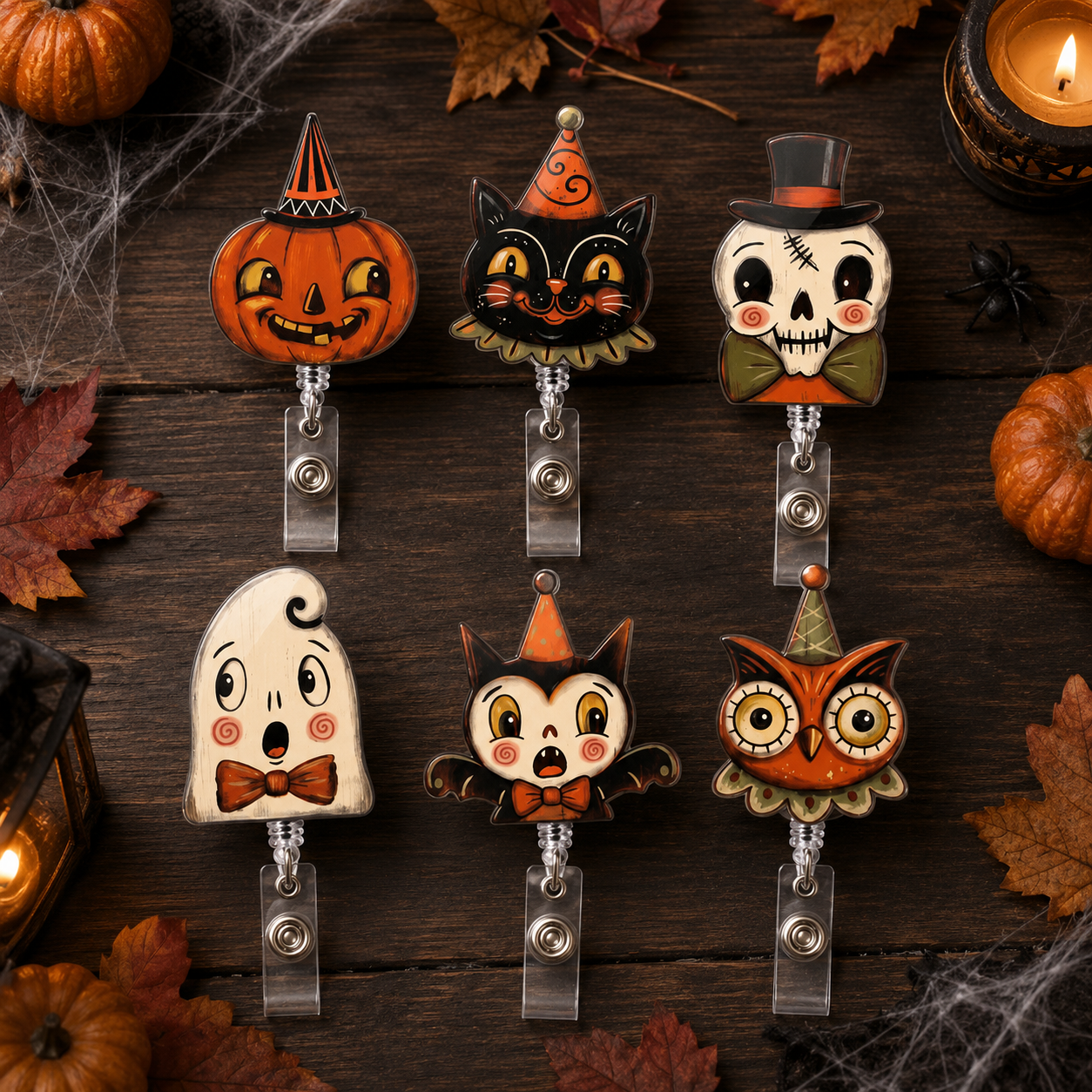 Six Halloween-themed retractable badge reel holders are arranged on a dark wooden surface with autumn leaves, pumpkins, cobwebs, and a lit candle. The character designs include a jack-o'-lantern, a black cat in a witch hat, a skull in a top hat, a ghost with a bow tie, a chibi cat with bat wings, and an owl in a party hat.