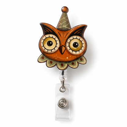 An owl-shaped retractable badge reel with a brown and orange face, large cartoon eyes, a pointed hat, and a clear plastic ID holder below, shown on a white background.