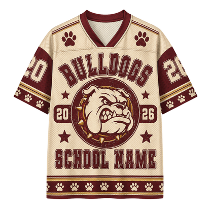 A short-sleeve V-neck football jersey with a cream mesh-like base and dark red graphics. The design features 'BULLDOGS' across the chest, a bulldog mascot logo in the center, paw prints, stars, and the placeholder text 'SCHOOL NAME'.