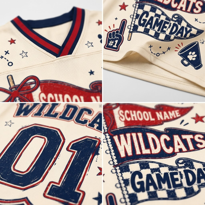 A close-up collage of a cream-colored athletic jersey with navy and red varsity-style graphics, including the word 'WILDCATS,' 'GAME DAY,' stars, a pom-pom graphic, and large number '01' on the front.