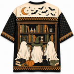 A short-sleeve crewneck t-shirt with an all-over Halloween-themed graphic print. The design features three ghosts in witch hats reading at a bookshelf, a black cat, pumpkins, a crescent moon, and bats on a cream and black background.