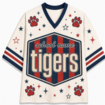 A cream-colored mesh athletic-style jersey with navy and red graphics, featuring a large 'school name Tigers' shield on the front, red paw prints, and scattered stars and stripes on the sleeves.