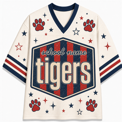A cream-colored mesh athletic-style jersey with navy and red graphics, featuring a large 'school name Tigers' shield on the front, red paw prints, and scattered stars and stripes on the sleeves.