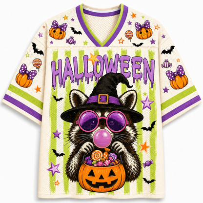 A short-sleeve V-neck jersey-style shirt with a Halloween theme. The cream-colored mesh fabric features purple and lime green trim, 'HALLOWEEN' text, bats, pumpkins, stars, and a central raccoon wearing a witch hat and purple bubbleglasses while holding a jack-o'-lantern candy bucket.