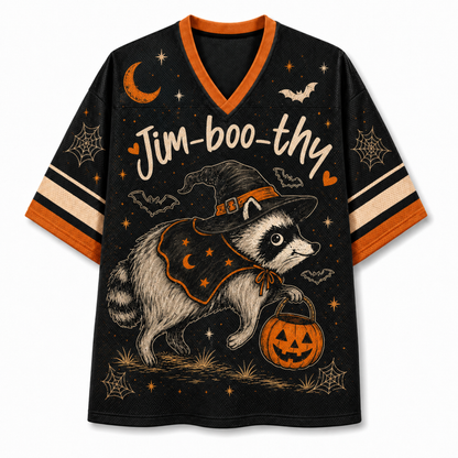 A black V-neck athletic-style T-shirt with orange trim and striped sleeves, featuring a large Halloween graphic of a raccoon in a witch hat holding a jack-o'-lantern, with stars, bats, spiderwebs, and the text 'Jim-boo-thy' across the front.