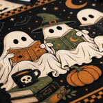 A close-up of a Halloween-themed textile or rug pattern featuring cartoon ghosts reading old books, with a black mug, books, stars, bats, and pumpkins on a dark background.