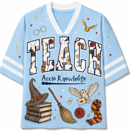 Front view of the baby blue varsity jersey displaying 'TEACH Accio Knowledge' surrounded by a magic broom, sorting hat, owl with acceptance letter, and wizard scarves.