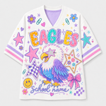 A white V-neck athletic-style shirt with colorful school-themed graphics, including the word "EAGLES" in large multicolored letters, a purple-and-white eagle illustration, stars, flowers, bows, smiley faces, and the text "School name" on the front.