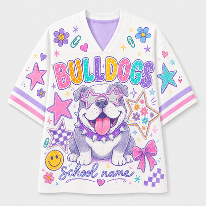 A white V-neck short-sleeve t-shirt with a colorful cartoon bulldog graphic, the word 'BULLDOGS' in rainbow letters, and 'School name' written at the bottom, shown on a light gray background.