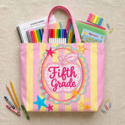 Pink tote bag with 'Fifth Grade' design filled with school supplies on a beige background