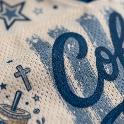 Close-up of a cream-colored mesh fabric with a blue distressed graphic print featuring the letters 'Co', stars, a coffee cup, and a cross.
