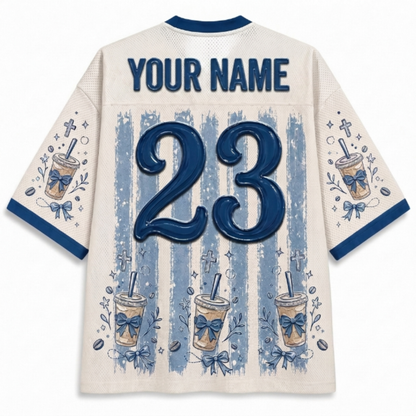 Back view of a customizable cream-colored jersey with blue trim, featuring a large blue number 23, 'YOUR NAME' text, and blue-and-white striped coffee cup graphics.