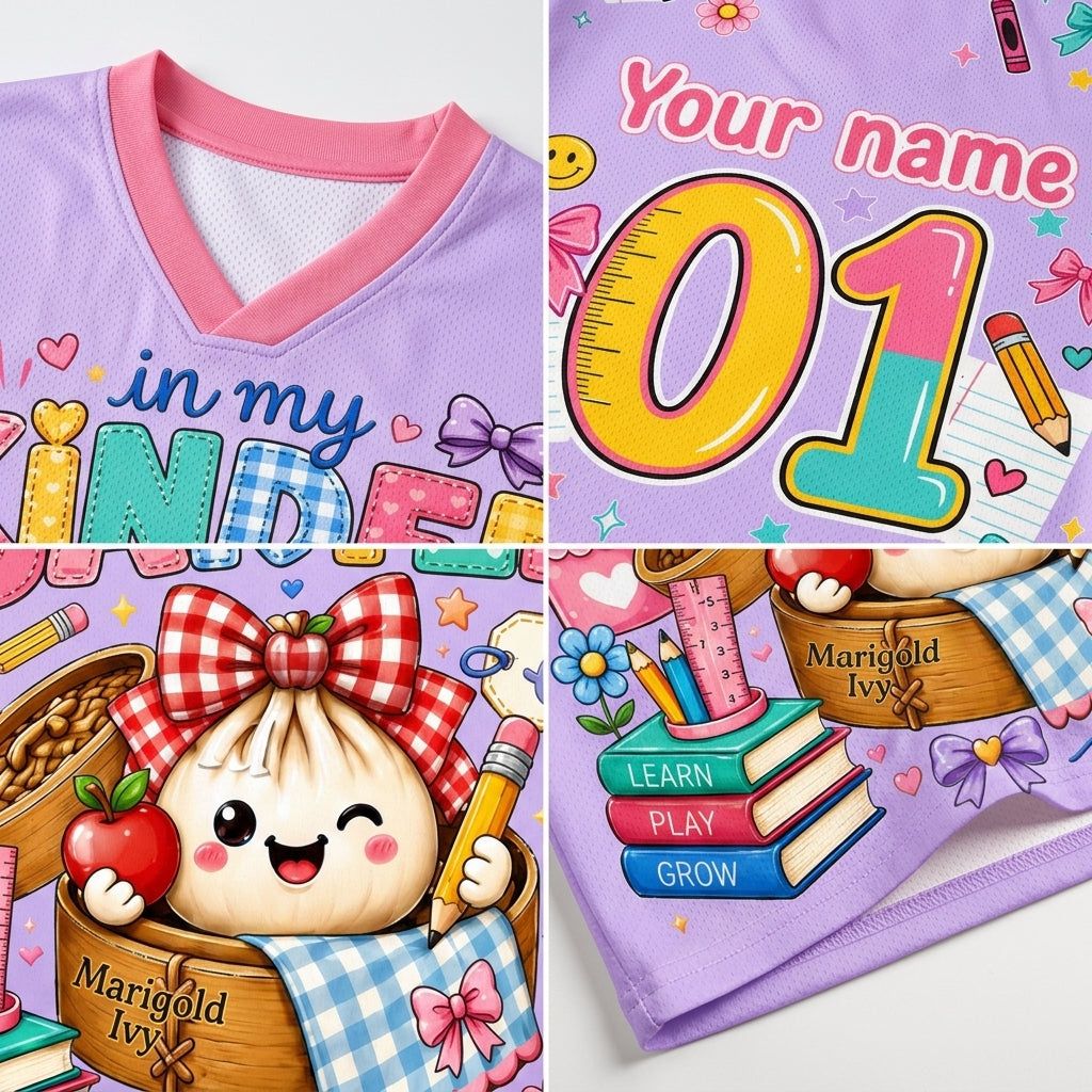 A collage showing a children's V-neck t-shirt with customizable printed graphics. The shirt features a light purple base with a pink collar, decorated with cute cartoon illustrations including a smiling dumpling in a basket, books, pencils, and the text 'Your name', 'in my KIND', and 'Marigold Ivy'.