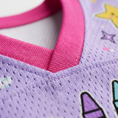 Close-up of a children's knit top showing a lavender purple body with a bright pink ribbed V-neck trim and small pastel star and crayon graphics.