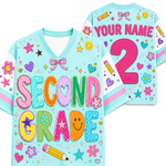A light blue custom kids' sports jersey shown from both the front and back. The front features colorful patchwork-style letters spelling 'SECOND GRADE' with school-themed motifs like stars, smiley faces, flowers, and a pencil.