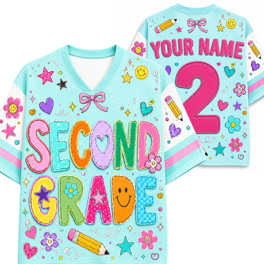 A light blue custom kids' sports jersey shown from both the front and back. The front features colorful patchwork-style letters spelling 'SECOND GRADE' with school-themed motifs like stars, smiley faces, flowers, and a pencil.