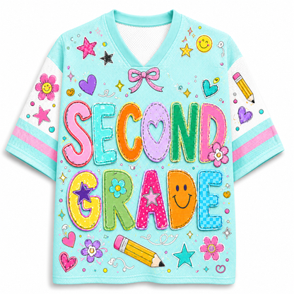 A light blue short-sleeve V-neck t-shirt with a colorful 'SECOND GRADE' patchwork graphic on the front, decorated with stars, hearts, smiley faces, flowers, and a pencil.