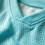 Close-up of a light aqua mesh V-neck athletic shirt showing the textured fabric and collar stitching.