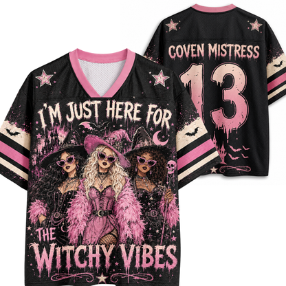 Black V-neck graphic jersey shown from front and back on a white background. The front features pink and beige witch illustrations with the text 'I'M JUST HERE FOR THE WITCHY VIBES'.