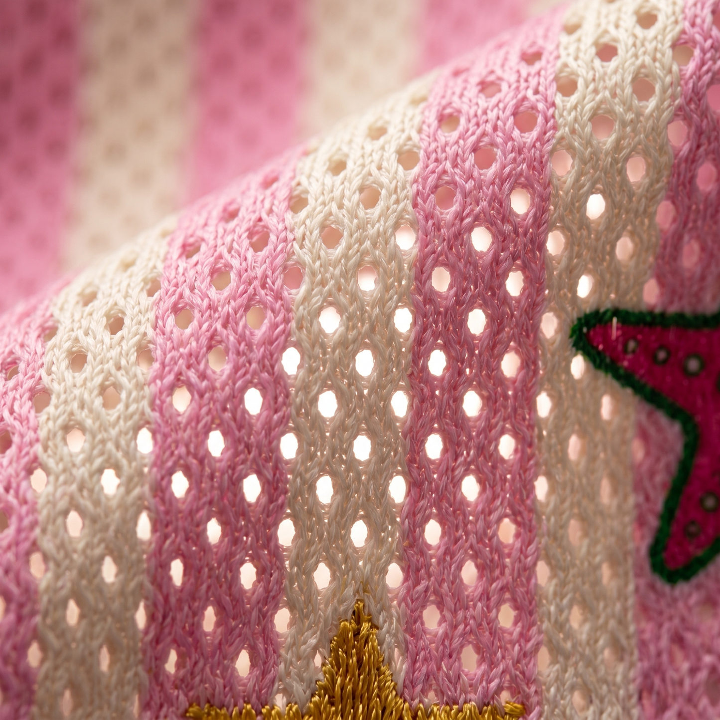 Extreme macro shot of the ChaoticClub pink and white striped mesh jersey fabric, highlighting the breathable knit texture with sunlight passing through the holes, featuring a close-up of a pink starfish and yellow star.