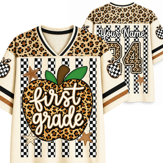 A custom first-grade themed athletic jersey shown from both front and back. The design features a leopard print apple graphic with the text 'first grade' on the front, checkered stripes, and a leopard print number 24 on the back with the placeholder 'Your Name'.