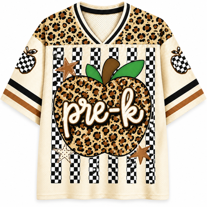 A short-sleeve V-neck athletic-style shirt with a cream base, leopard-print panels, black-and-white check stripes, and a large central apple graphic reading 'pre-k' in script.