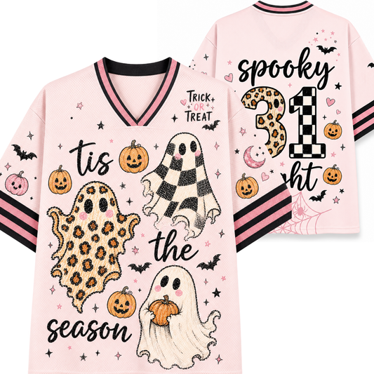A light pink Halloween-themed short-sleeve V-neck T-shirt shown from both front and back. The front features playful spooky graphics including leopard-print and checkered ghosts, jack-o'-lanterns, bats, stars, and the text 'tis the spooktiest season' with 'Trick or Treat' above.