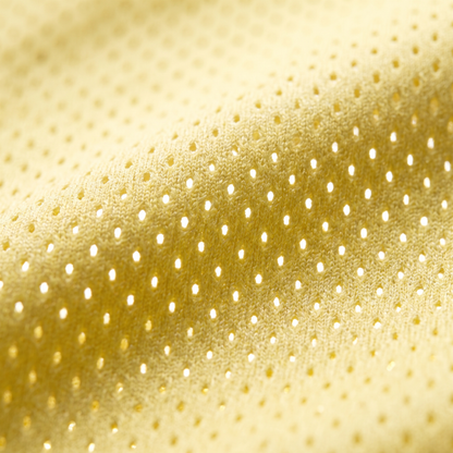 Extreme macro shot of the yellow pro-mesh breathable fabric, highlighting the airy knit texture designed for maximum comfort during hot summer days.