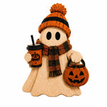 A wooden ghost-shaped Halloween decoration wearing an orange and black striped knit hat with a pom-pom, a matching plaid scarf, holding an orange jack-o'-lantern bucket, and a drink cup with a black straw, isolated on a white background.