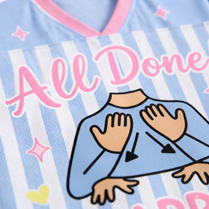 Close-up of a light blue and white striped athletic jersey with pink trim, featuring the words 'All Done' in pink script and a cartoon illustration of a person's arms and hands in a self-care or meditation pose.