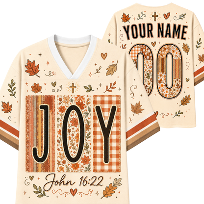 Personalized Thanksgiving football jersey shown from both front and back on a white background. The cream-colored jersey features autumn leaf and heart patterns, a V-neck, and 'JOY' and 'YOUR NAME 00' printed in black with patterned fillings.