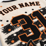 Close-up of a custom sports jersey featuring a large black number 31 with an orange outline, black and white distressed stripes, orange and white polka dots, and the text 'YOUR NAME' on a cream-colored mesh fabric.