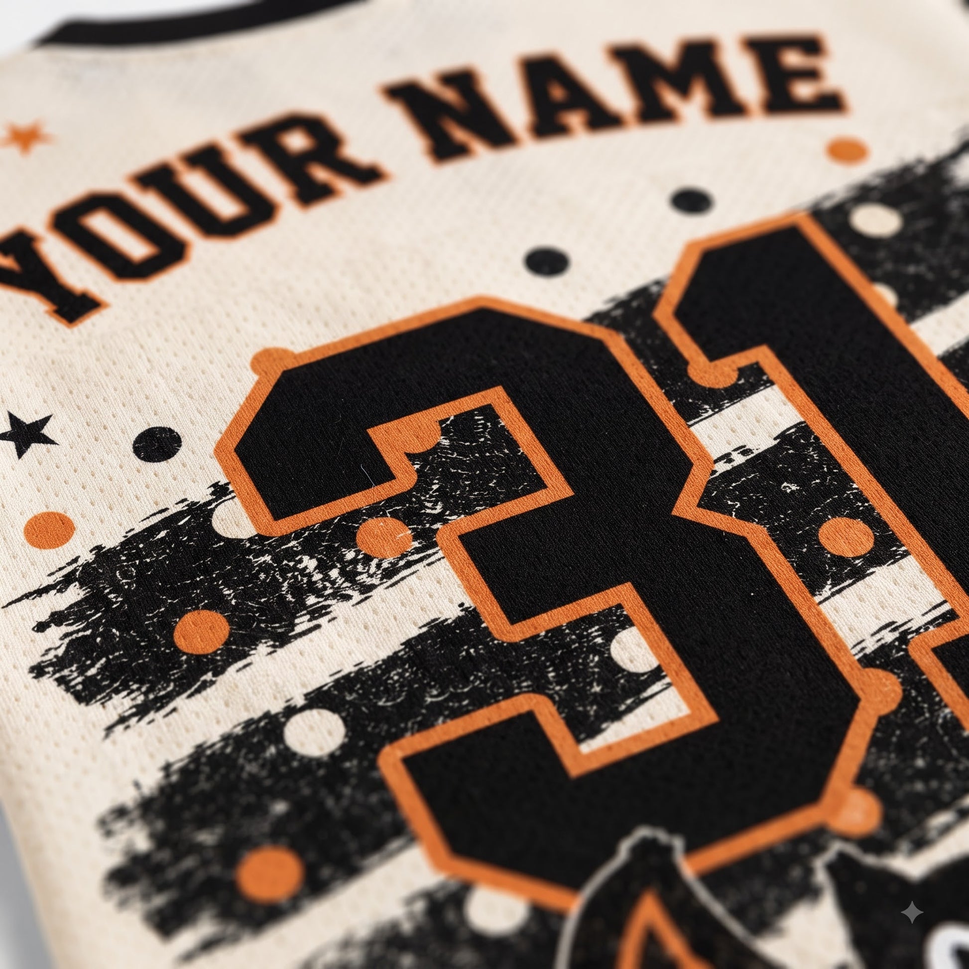 Close-up of a custom sports jersey featuring a large black number 31 with an orange outline, black and white distressed stripes, orange and white polka dots, and the text 'YOUR NAME' on a cream-colored mesh fabric.