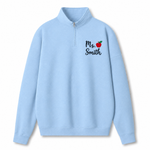 A light blue quarter-zip sweatshirt with a mock neck collar, featuring the text 'Ms. Smith' and a small red apple graphic printed on the left chest, displayed on a clean white background.