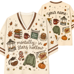 A cream-colored V-neck t-shirt with brown trim, featuring autumn-themed illustrations and the text 'mentally in stars hollow' on the front. The back view shows customizable text reading 'your name' along with additional seasonal graphics.