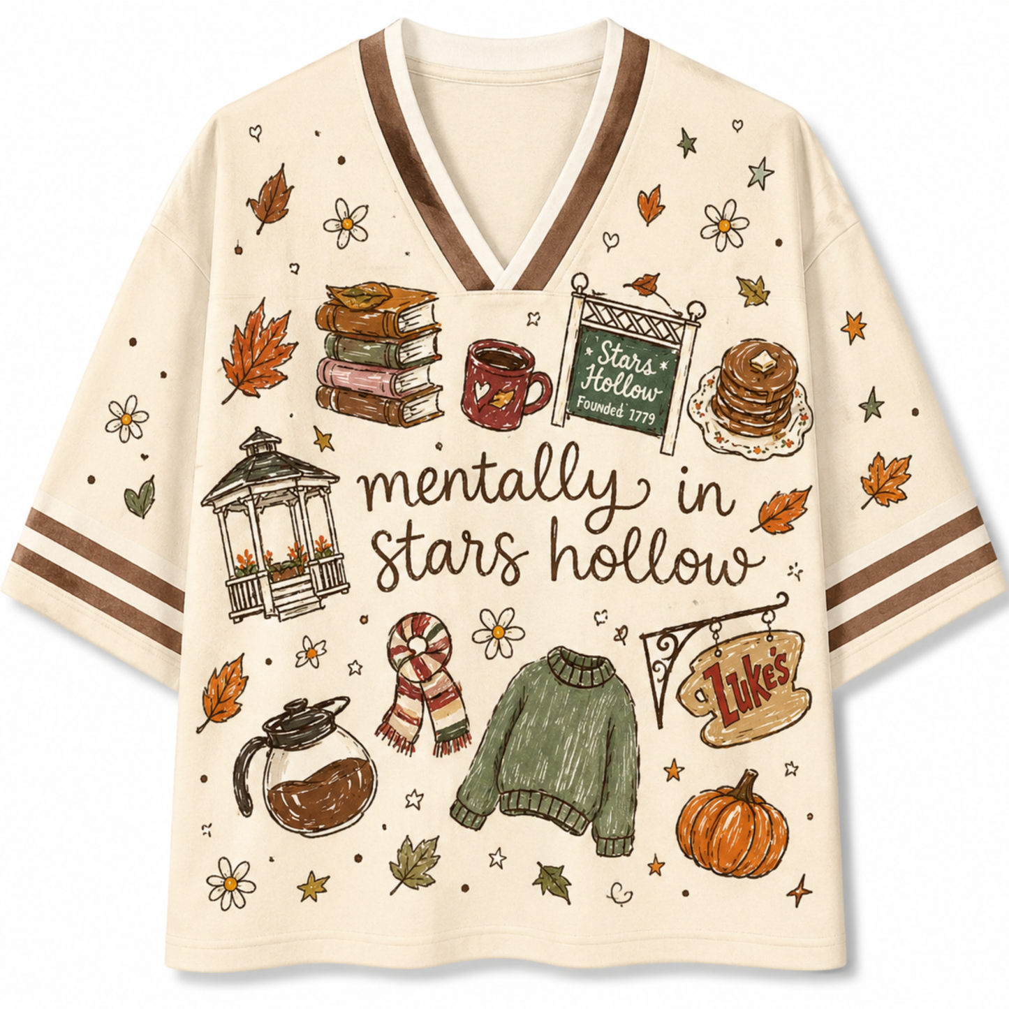 A cream-colored short-sleeve V-neck T-shirt with brown stripes on the sleeves and a detailed autumn-themed graphic print featuring books, a mug, pancakes, a sweater, a pumpkin, and the text 'mentally in stars hollow'.