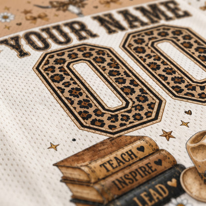 Close-up of a custom sports jersey print featuring leopard-print '00' numbers, 'YOUR NAME' text, stars, books with 'TEACH INSPIRE LEAD', and a cowboy hat on an off-white mesh fabric.