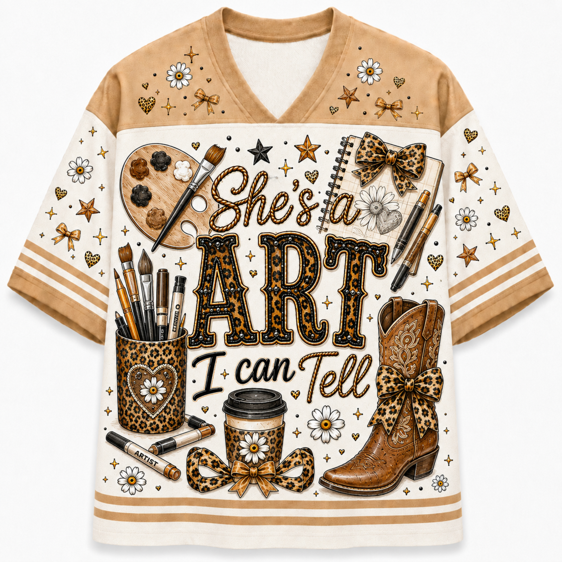 A short-sleeve V-neck t-shirt with a cream and tan base, featuring a detailed graphic print on the front. The graphic includes the text 'She's a ART I can Tell' in leopard-print outlined letters, surrounded by artistic and western-themed illustrations such as a paint palette, brushes, cowboy boots, bows, stars, and daisies.