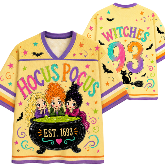A yellow V-neck t-shirt with a colorful 'Hocus Pocus' Halloween graphic, shown in both front and back views. The shirt features cartoon witches in a cauldron, the text 'HOCUS POCUS' and 'WITCHES 93' in rainbow lettering, and illustrations of black bats and a black cat on a broomstick.