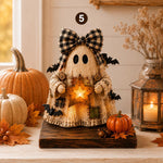 A rustic Halloween ghost decoration made from light wood with a black-and-white gingham bow, holding a glowing star, displayed on a wooden stand among pumpkins, autumn leaves, and a lantern.