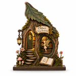 A decorative fairy-themed woodland house figurine with a leaf-shaped roof, mossy details, a small door, window view of bookshelves, a lantern, mushrooms, flowers, and an open book on a white background.